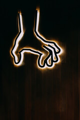 Grabbing hand sign with light around it, on a dark wooden background, copy space