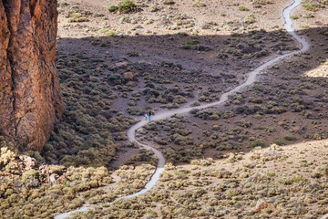 Woman trekking with child on a curvy path in desert landscape