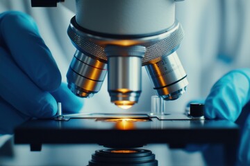 Close-up of a scientist using a microscope to examine sample slides in a laboratory setting with gloves and focused lighting.