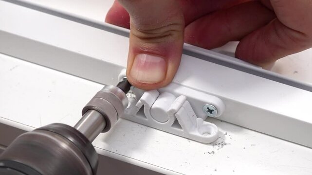 Close up view of snap lock mechanism screwing to fly screen window with an electric drill.