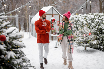 Man and woman talk and drink while spending winter time together at beautifully decorated snowy...