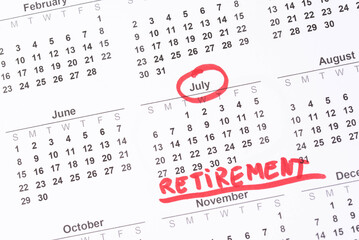 Hand fills in a large wall calendar, counting down the days until retirement, writing 'Retirement'. Concept of early retirement, the Financial Independence, Retire Early movement (FIRE)