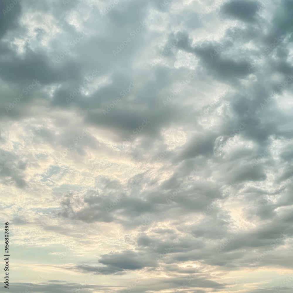 Wall mural Overcast sky with grey and white clouds, sun peeks through.