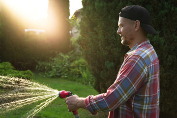 Man watering lawn with hose in backyard