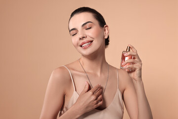 Smiling woman with bottle of perfume on beige background