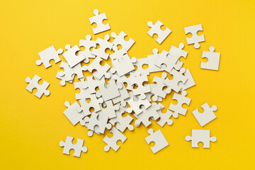 White puzzle pieces on yellow background, top view