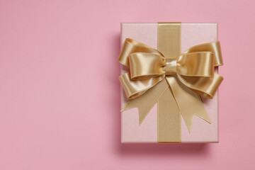 Gift box with bow on dusty pink background, top view
