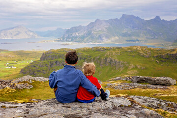 Happy children with parents and dog, european family, hiking the Kvalvika trail on hill at Kvalvika beach, Norway