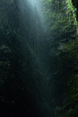 Obraz premium Creative and artistic composition in the Cueva del Esplendor, cave of splendor, Jardin, Jardín, Antioquia, Colombia. Dark abstraction with rain falling on a rock and droplets in a ray of light.