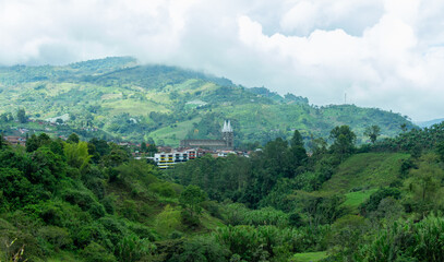 Cityscape of Jardin, Jardín, Antioquia, Colombia. Awesome landscape with the green Andes Mountains. Cloudy sky. Lush vegetation. Church.