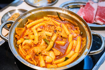 Korean Instant Tteokbokki with Ramen Noodles and Blurred Beef Background