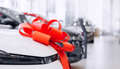 Luxury new cars with red ribbon bow in showroom waiting for sale to customer, blur background sunlight