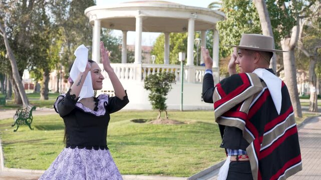 pareja de huasos chilenos bailando cueca en la plaza de la ciudad, concepto celebraci&oacute;n fiestas patrias 
