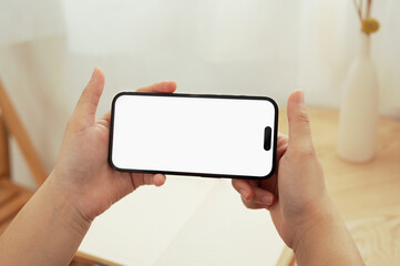 Close up view of woman hands holding a smartphone with empty screen in landscape orientation