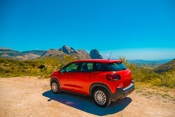 Red car stopped on dirt road in mountains of Andalucia