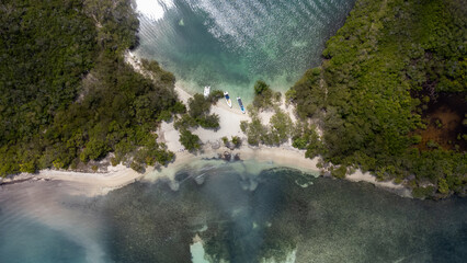 Three boats on a small patch of white sand among crystal clear waters