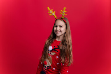Teen girl wearing Xmas sweater and antlers isolated on red. Merry Christmas. New Year holiday in winter. Teen girl having fun. Happy 2024 New Year. Christmas shopping sale. Festive cheer