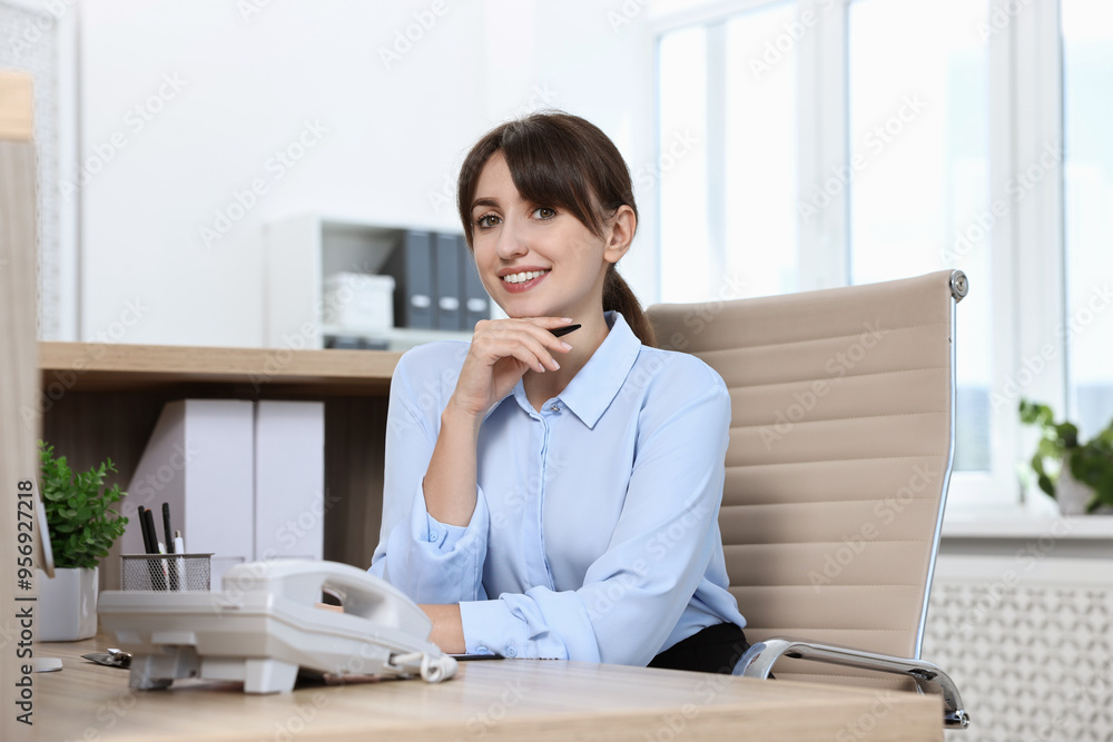 Wall mural Portrait of receptionist at wooden desk in office