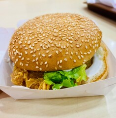 hamburger on wooden background. Chicken burger with salad and mayonnaise. closeup of sloppy assembled or cooked burger taken away from restaurant.