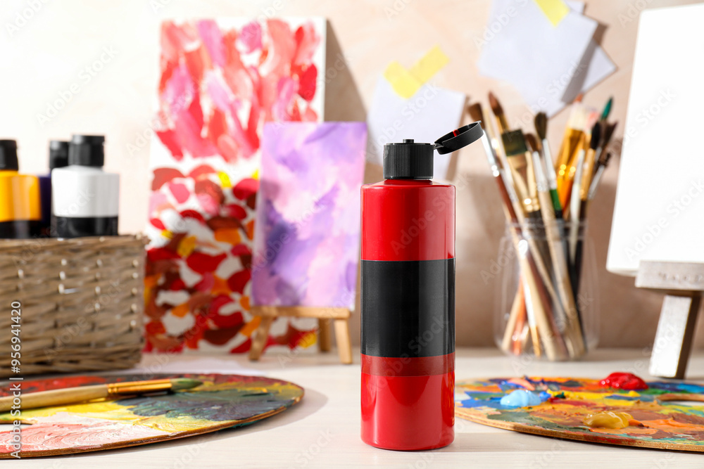 Poster Red acrylic paint in bottle, small easels, palettes and brushes on wooden table indoors