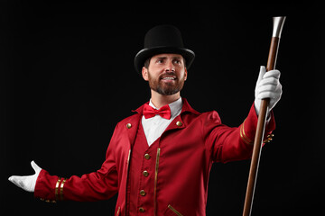 Portrait of showman in red costume and hat on black background