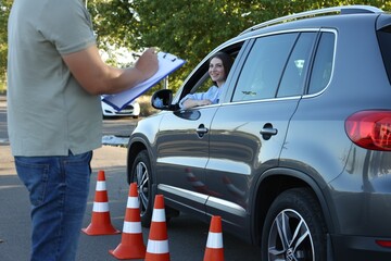 Examiner with clipboard during exam at driving school test track, closeup