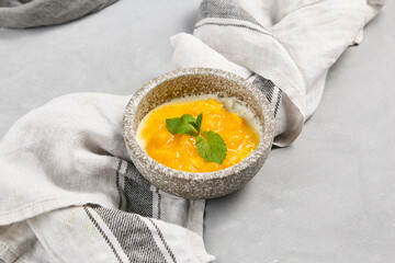 Close-up of Panna Cotta with Mango Topping in Rustic Bowl on Linen Cloth