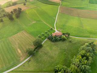 Aerial view of farm house in rural area in Switzerland. Road through fields.