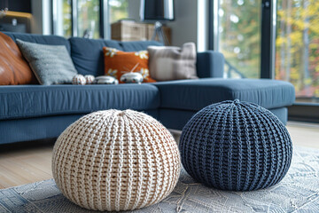 Two knitted poufs sit near a dark blue corner sofa, creating a modern Scandinavian home interior design in a cozy living room 