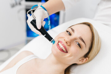 A cosmetologist performs hydropeeling, deeply cleansing and rejuvenating the client's skin in a...