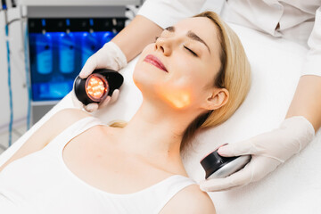 A cosmetologist performs LED light therapy for facial rejuvenation. This non-invasive treatment...