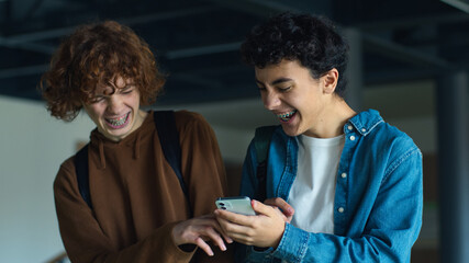 University back to school Caucasian two boys teens pupils students people guys male friends talking smiling laughing talk using mobile phone surprise shocked excited walk studying education teenagers