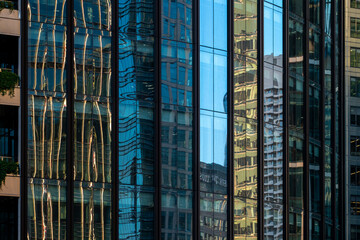 Abstract reflections of assorted urban architecture on colorful glass windows, presenting a kaleidoscopic view of the city's dynamic and modern landscape amid light play.