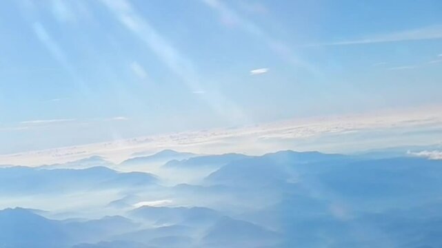Aerial view of Apennine Mountains in couds and mist, sun rays and horizon with blue sunny sky above. Topics: Apennines, air travel, space over land, Italy, Europe, weather, meteorology, vacation
