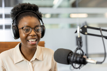 African American businesswoman hosting podcast wearing headphones. Engaged in recording session with microphone in modern office. Highlights professional communication and creative engagement