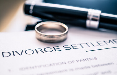 Detailed View of Divorce Settlement Agreement with Wedding Ring and Pen on Document Signifying...