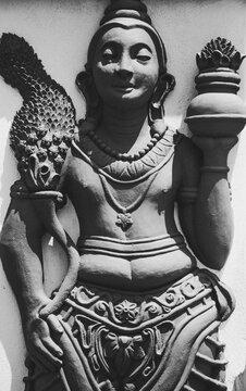 Black and white carved statue of a smiling man.