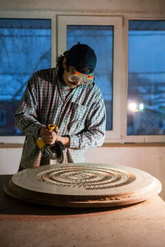 Skillful carpenter artistically engraving wood in his atelier 