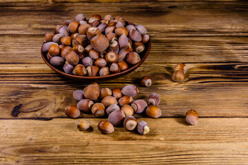 Plate with pile of hazelnuts on a wooden table