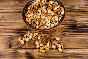 Various nuts (almond, cashew, hazelnut, pistachio, walnut) in ceramic plate on a wooden table. Vegetarian meal. Healthy eating concept