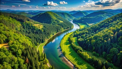 Fototapeta premium Serene aerial view of a winding river flowing through a lush green valley surrounded by dense forests and rugged hills under a clear blue sky.