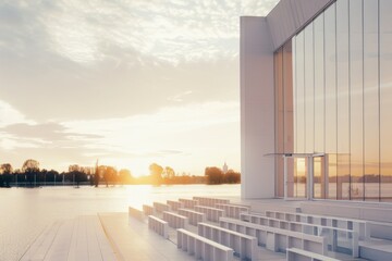 An outdoor seating area by a large glass building, bathed in the glow of the setting sun, reflecting tranquility and modern architecture.