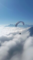 Paraglider Flying Above the Clouds with Mountain View