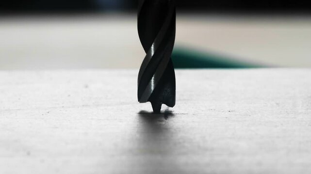 A close-up shot of a drill bit starting to penetrate a surface, showcasing precision in drilling work.