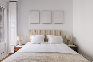 A minimalist bedroom with a large bed with a beige tufted headboard