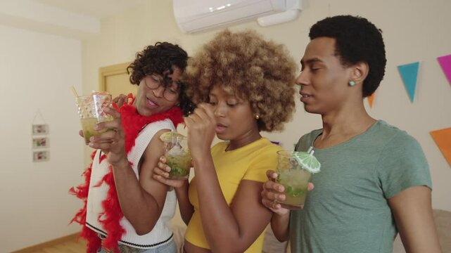 LGBTQIA group, two Latino men and a Black woman, having fun with mojitos and dancing