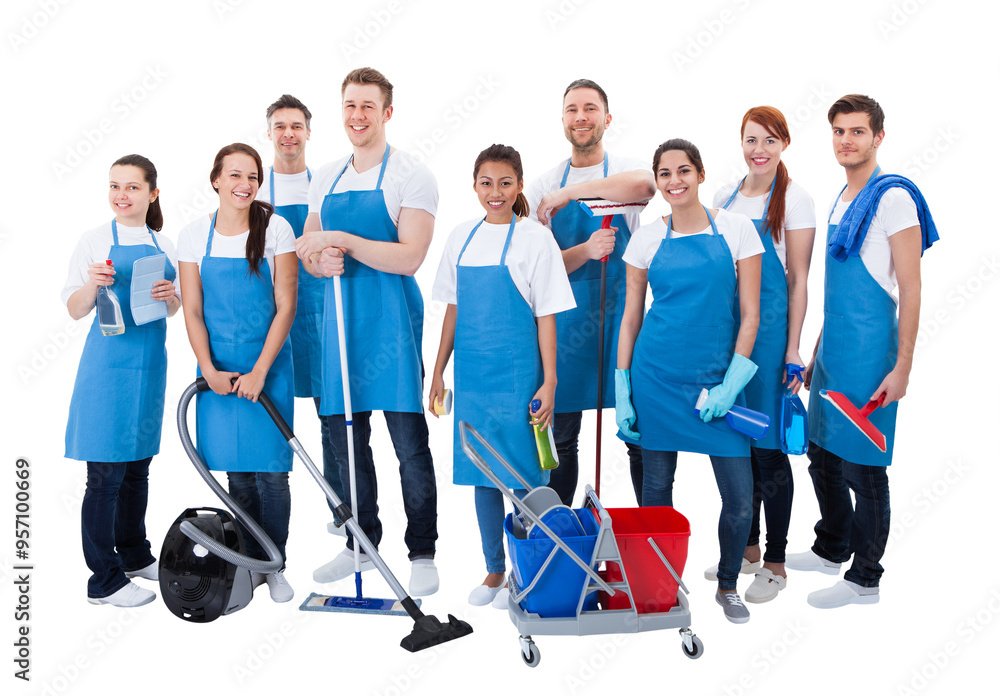 Wall mural Smiling janitorial team in blue aprons with cleaning equipment isolated