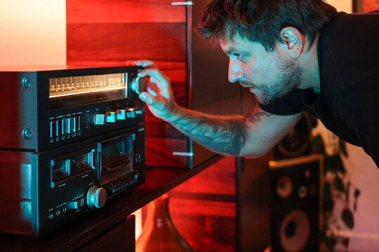 Man at night selecting song to play on the radio with cozy soft light