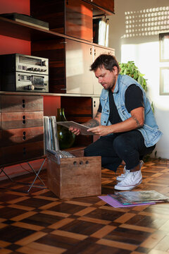 Portait man pick up vinyl record on wooden vintage parquet  floor