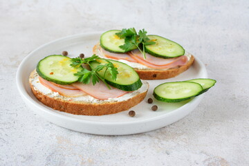 a sandwich of ham, cheese and cucumber on a table